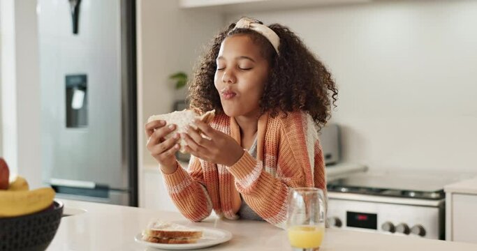Smile, eating and kid with sandwich in kitchen for nutrition, child development and healthy diet. Hungry, little girl and table with food at home for lunch, satisfaction and happiness in house