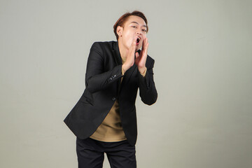 portrait of happy asian businessman wearing suit shouting with cupping hand on isolated background