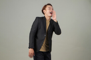 portrait of happy asian businessman wearing suit shouting with cupping hand on isolated background