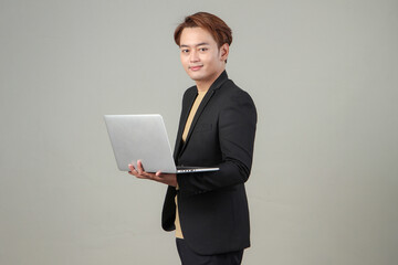 portrait of happy asian businessman holding laptop computer wearing suit on isolated background