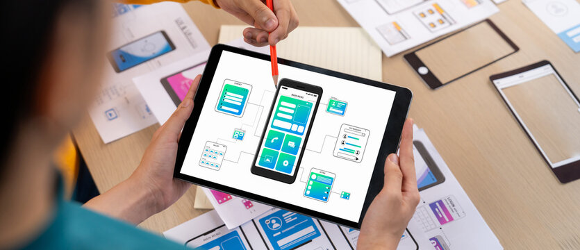 Panorama banner of startup UX developer or company employee design user interface or UI prototype for mobile application or website software with software display on tablet screen in office. Synergic