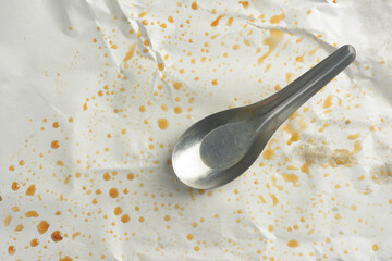 A used spoon rests on a discarded rice paper wrapper.