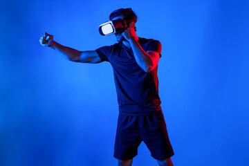 Side view of smart man wearing VR glass and smashing or punching at camera. Sport gamer boxing and...