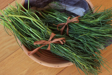 Bunch of fresh Salsola soda in a basket on wooden table. Italian Barba di frate or Agretti or...