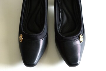 A pair of woman's leather black shoes on a white background