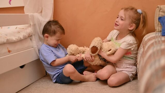 Battle for the toy. Children cannot share a soft toy in the children's room. Brother and sister, confrontation