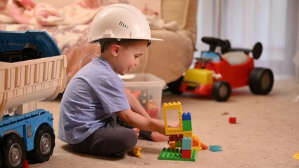 A child in a builder's helmet builds a tower from a constructor in a children's room. Slow motion