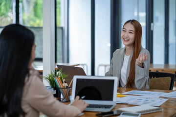 Two Asian businesswomen working Creative discussion in office using laptop and tablet, business concept