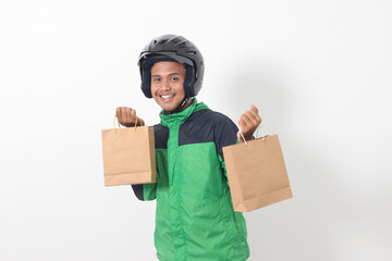 Portrait of Asian online courier driver wearing green jacket and helmet giving craft paper shopping...