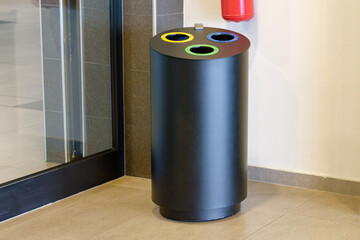 Metal trash can for disposing of plastic, paper and waste placed next to a wall in the hallway of a...