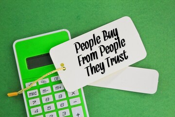 calculator and a paper tag with the words People Buy From People They Trust. business concept. the...