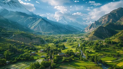 Aerial view of the Hunza Valley in Pakistan, featuring its lush green valley surrounded by snow-capped peaks and traditional villages.     