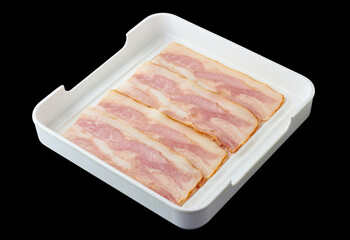 Raw smoked bacon placed in a white tray isolated on black background.
