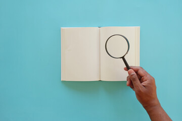 open book and magnifying glass on table.