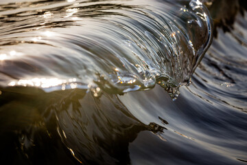 Sunlight reflecting off the crest of a miniature breaking glass wave