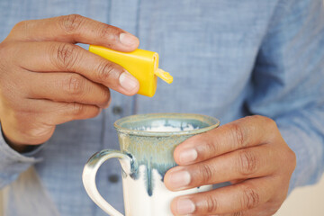 young man putting artificial sweetener in tea,