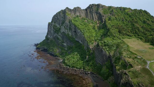 Drone footage of Seongsan Ilchulbong peak on a sunny day in Seogwipo-si, Jeju Island, South Korea