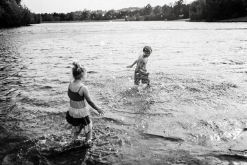 Artsy monochrome of kids splashing in lake on sunny day