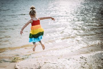 Young child joyfully jumping near lake shore
