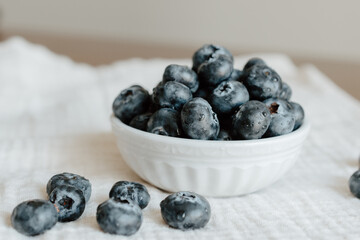 Fresh blueberries in a white bowl on a cloth