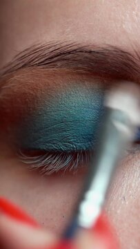 Makeup artist applies makeup to the upper eyelid close-up. Blends bright shadows with a makeup brush. Training master class on professional makeup