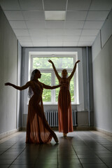 Silhouette of two dancers rehearsing choreography in the hallway of theatre
