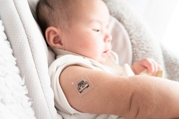 Band-aid with character on it on baby's right arm with red skin after vaccination