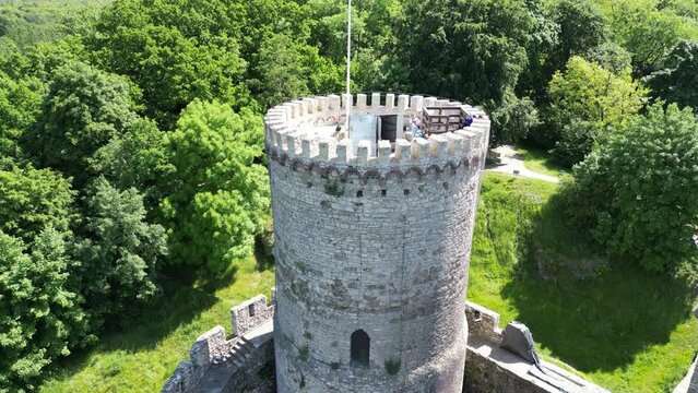 Medieval Bedzin castle with a turret, walls, and courtyard during a beautiful summer day surrounded by lush greenery, grass, and trees under a clear blue sky