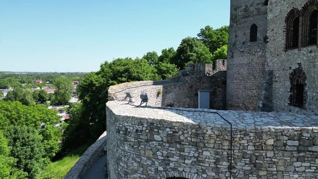 Medieval Bedzin castle with a turret, stone walls, and courtyard during a beautiful summer day surrounded by lush greenery, under a clear blue sky