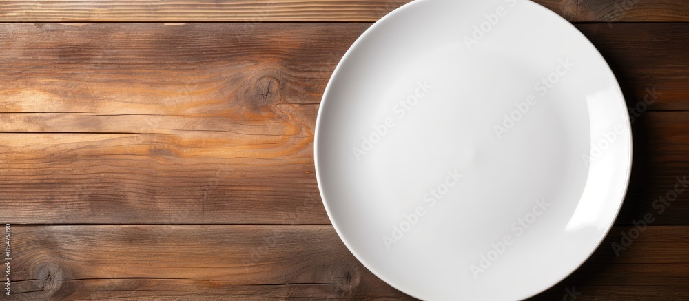 Poster top view of a white ceramic plate placed on a wooden background and there is ample copy space in the