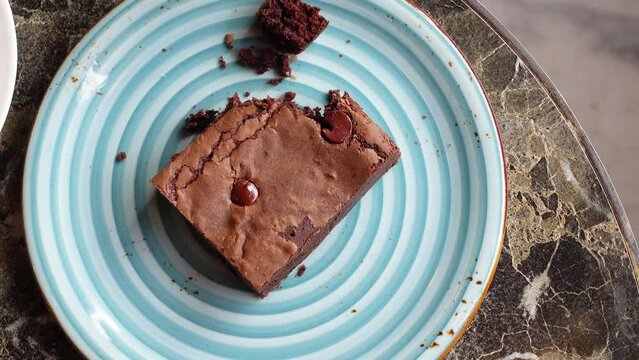 cutting a brownie with a fork on plate on table 