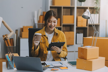 Asian SME business women use laptop computer checking customer order online shipping boxes at home....