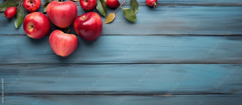Aufkleber A copy space image featuring a rustic wooden board adorned with a heart leaves and an arrangement of vibrant red apples set against a backdrop of a serene blue background