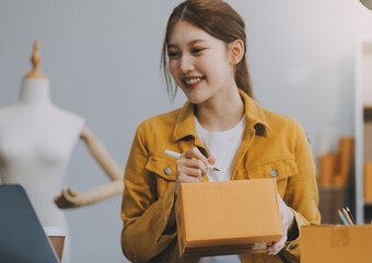 Asian SME business women use laptop computer checking customer order online shipping boxes at home....