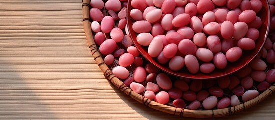 A pink plate holds numerous cherry stones arranged around a central opening set against a wicker carpet in the background creating a copy space image