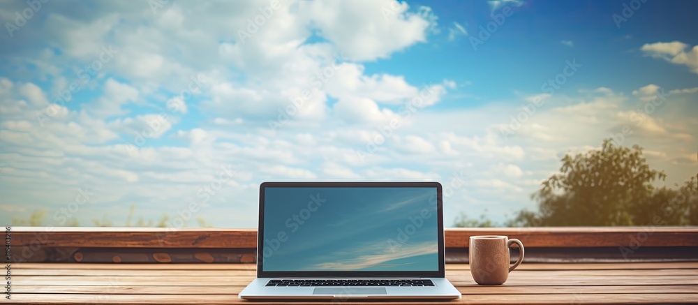 Poster A laptop resting on a wooden table with a serene sky as the backdrop Copy space image
