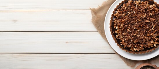 A flat lay photograph of a homemade Chocolate Walnut Derby Pie taken from above on a white wooden surface providing ample copy space