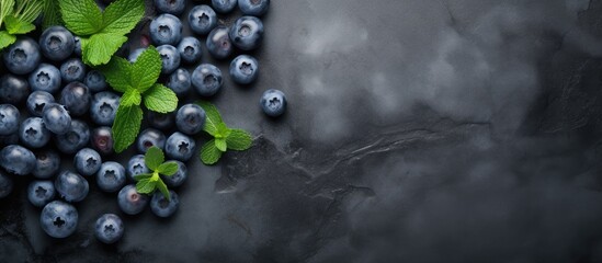 Top view of a stone gray background showcasing a healthy and detoxifying concept with a visually appealing arrangement of berry fresh blueberries and fresh mint leaves on a black slate board Ample sp