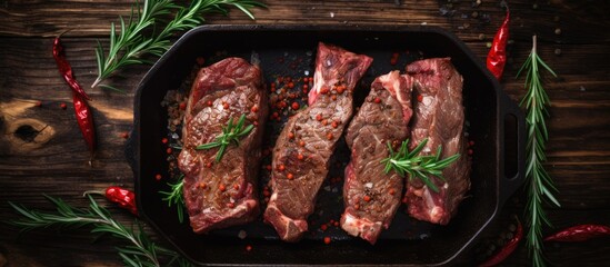 A top view of raw beef short ribs meat on a pan with herbs placed on a wooden background The image provides ample copy space