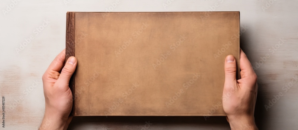 Fototapete top view of a male hand holding an empty antique style book with ample copy space for your message s
