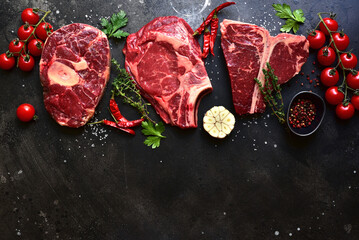 Raw organic marbled beef steaks : ossobuko, rib eye ( cowboy ) , T - bone. Top view with copy space.