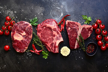 Raw organic marbled beef steaks : ossobuko, rib eye ( cowboy ) , T - bone. Top view with copy space.