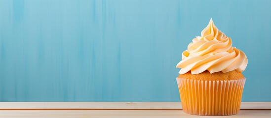 A delectable cupcake sits on a vibrant wooden table against a bright backdrop in this copy space image