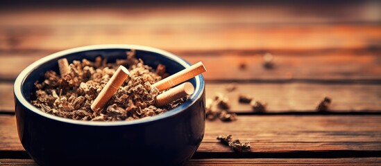 A close up image of cigarettes in an ashtray on a wooden background providing copy space