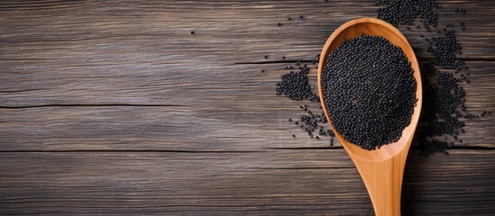 A copy space image showcasing black sesame seeds in a rustic wooden spoon on a tabletop