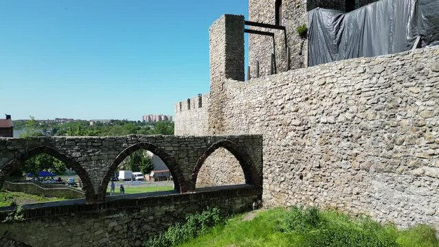 Medieval Bedzin castle with a turret, white stone walls, and courtyard during a beautiful summer day surrounded by lush greenery, under a clear blue sky