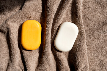 Two bars of body soap on a brown towel