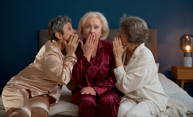 Three elderly female friends gossiping and laughing celebrating hen-party