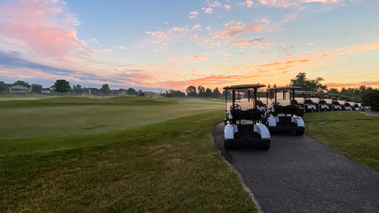 Golf Carts Lined Up Ready for the Day at Sunrise with Pink Skies