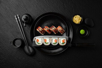 Canada Roll with salmon and Smoked Eel. Sushi composition on black background. The Art of Japanese...